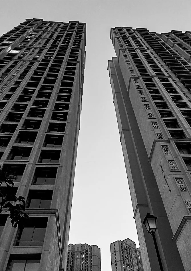 Black-and-white photograph looking up between two high-rise residential towers.